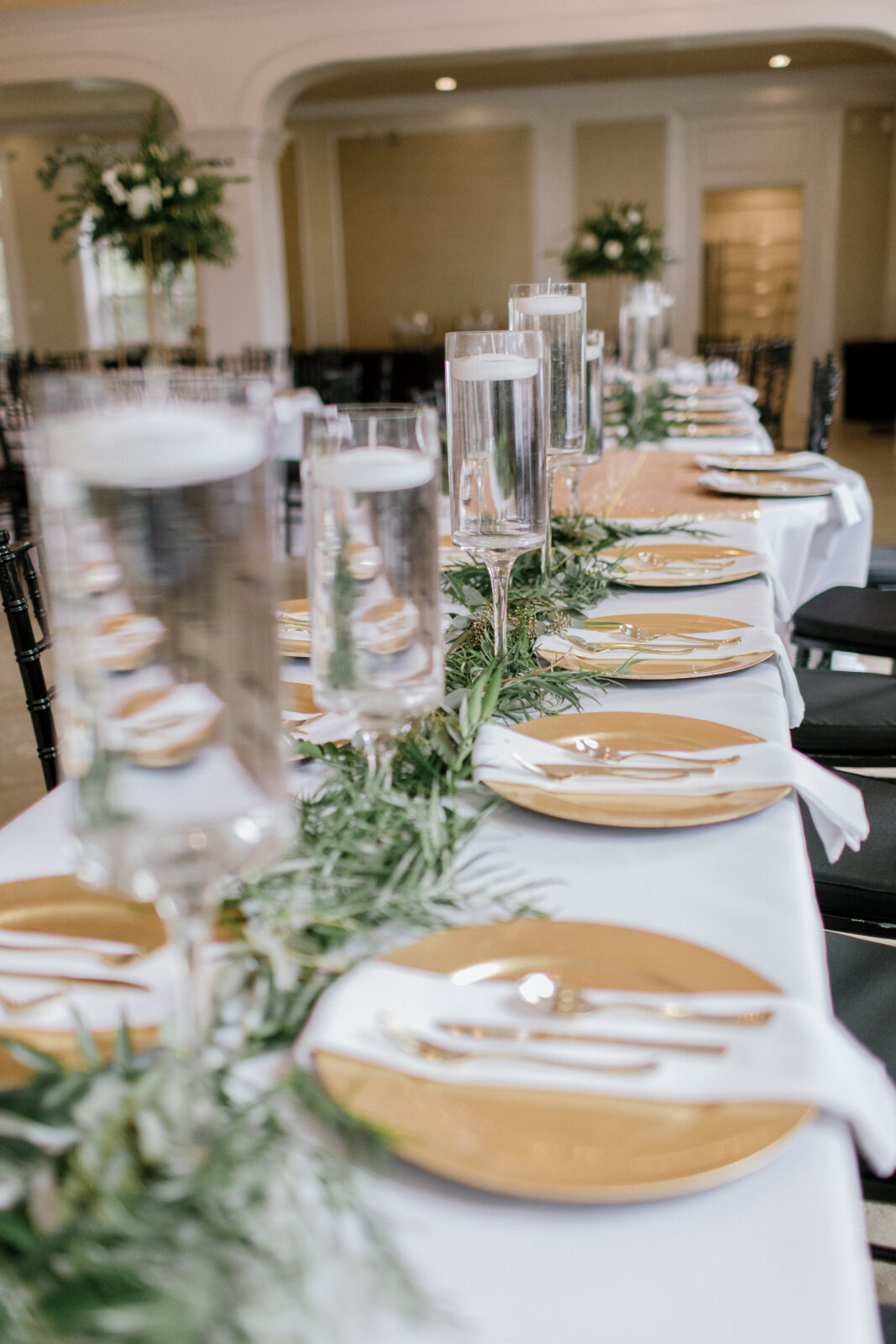 glass vases with white floating candles and golden chargers with white napkins