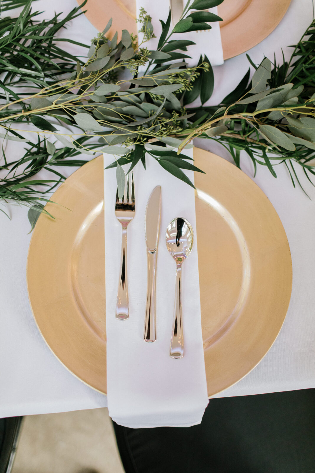 golden charger with white napkin and silverware on table